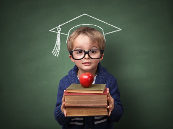 Child holding stack of books with mortar board chalk drawing on