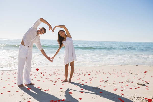 Loving couple forming heart shape with arms against red love hea